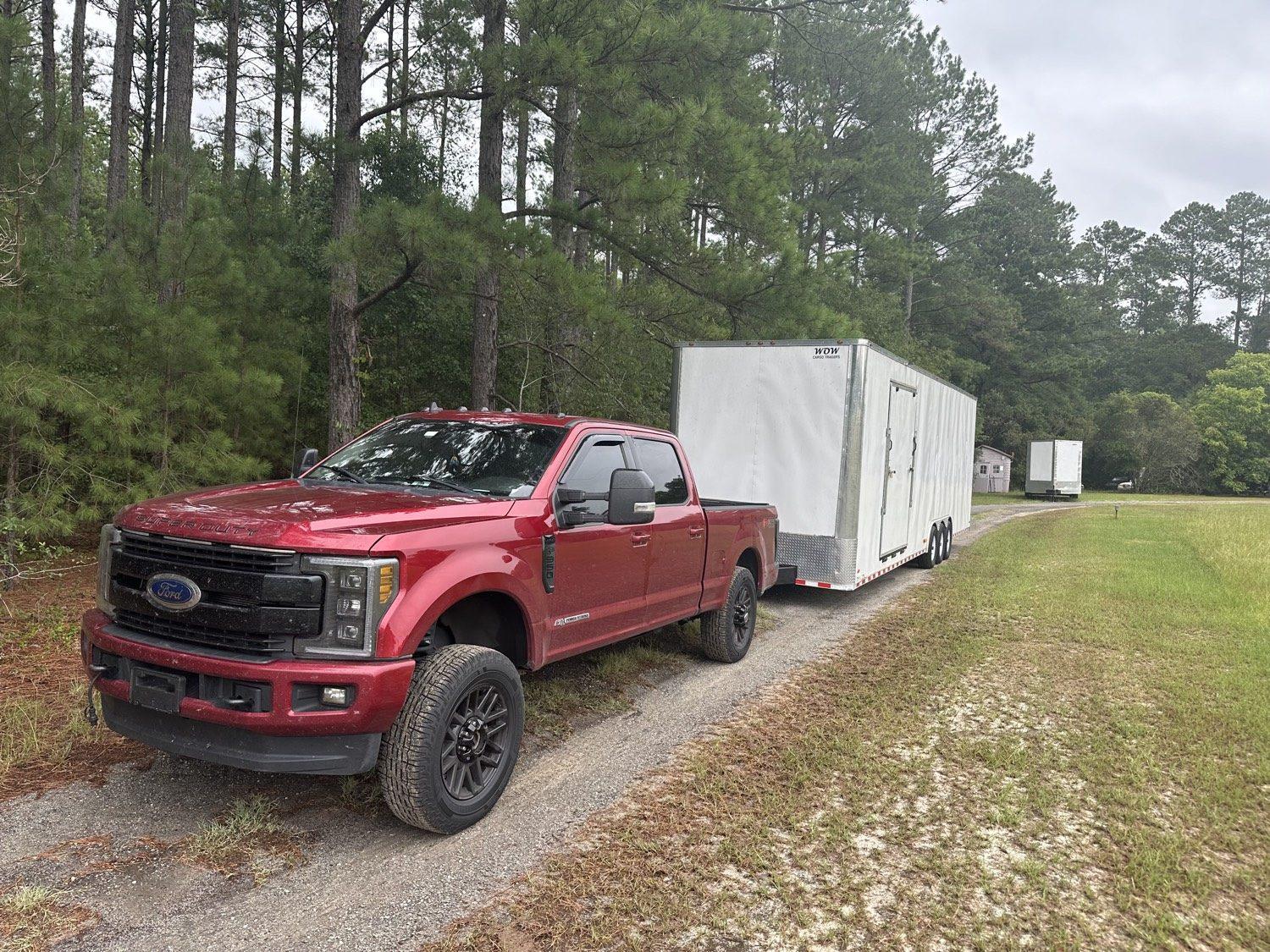 Red Super Duty towing a white enclosed cargo trailer